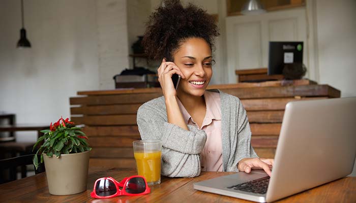 Admin-Questions Young woman talking on phone and using laptop